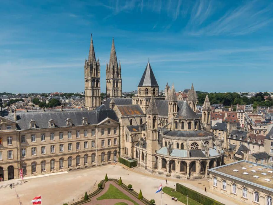 Vue aérienne de l'église Saint-Étienne et de l'Abbaye aux Hommes à Caen, France, avec un ciel bleu clair.